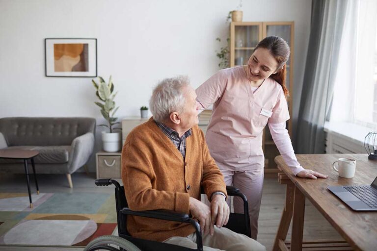 Older adults chatting together around a table in a bright, comfortable common room.