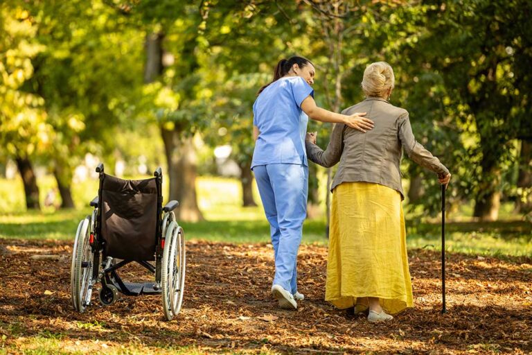 Older adult and family member speaking with a staff member in a bright assisted living common room.