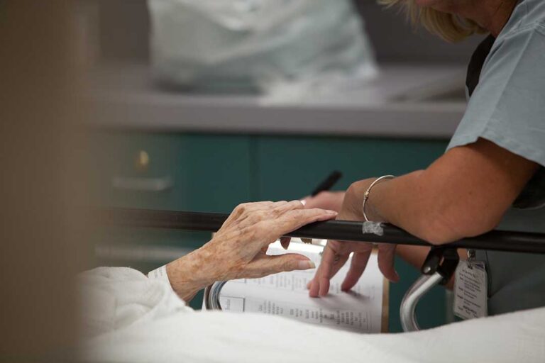 Older adult and family member reviewing Medicare paperwork at a table in an assisted living apartment.